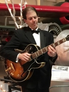 Dennis in tuxedo playing jazz guitar