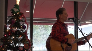 Dennis playing at holiday party for seniors with Christmas tree in background