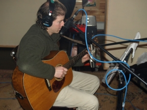 Dennis in recording studio with acoustic guitar