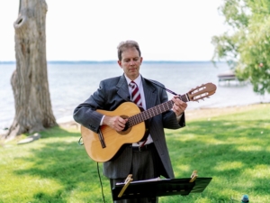 Dennis playing classical guitar at wedding ceremony on lake