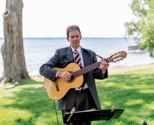 Dennis playing classical guitar at wedding ceremony on lake