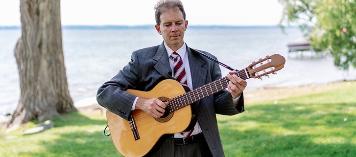 Dennis playing classical guitar at wedding ceremony on lake