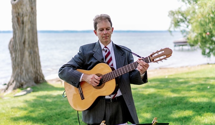 Dennis playing classical guitar at wedding ceremony on lake