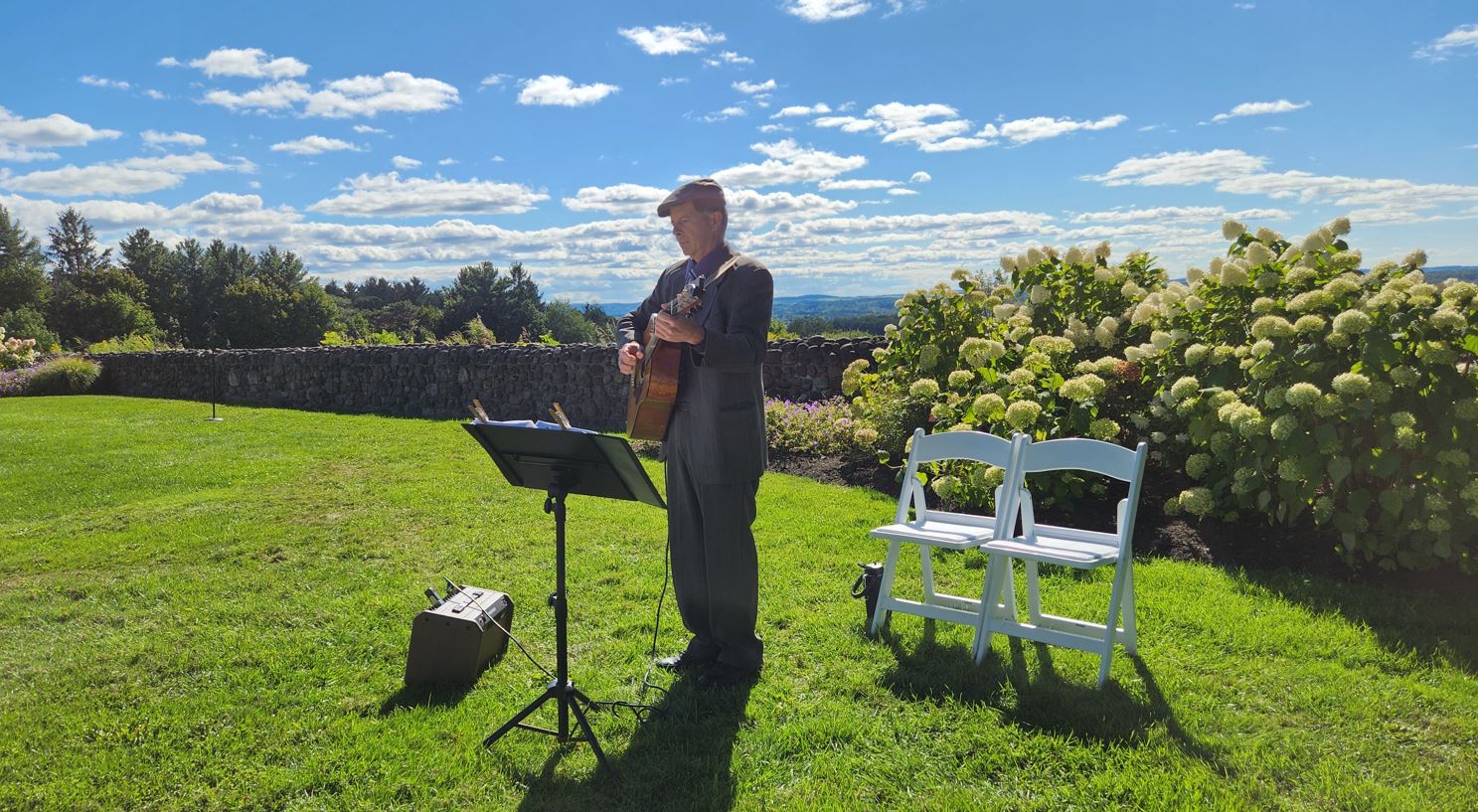 Dennis Winge playing acoustic guitar at wedding ceremony with beautiful view