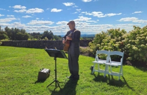 Dennis Winge playing acoustic guitar at wedding ceremony with beautiful view